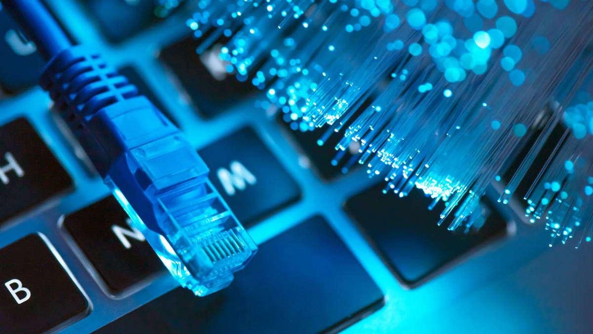 der-stecker-eines-lan-kabels-und-glasfasern-liegen-auf-einer-blau-beleuchteten-laptop-tastatur-adobe-stock-bildnr-409970625 der-stecker-eines-lan-kabels-und-glasfasern-liegen-auf-einer-blau-beleuchteten-laptop-tastatur-adobe-stock-bildnr-409970625